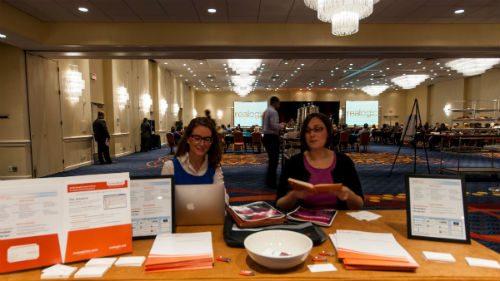 Amanda Grantham (left) and Amanda Gorman (right) staff the booth while the Realogic logo flashes on the big screens flanking the stage.